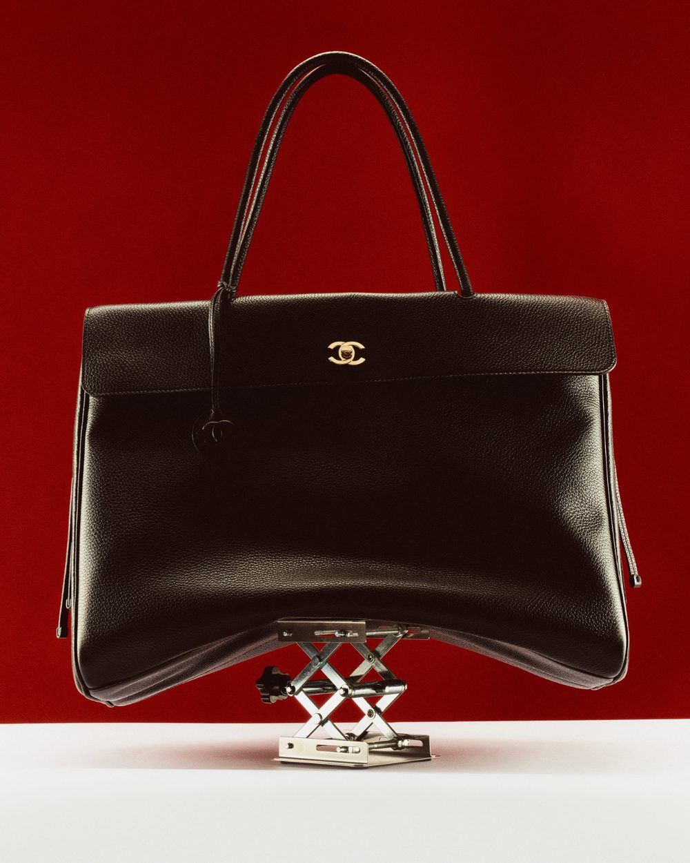 Black handbag balanced on a chrome scissor lift